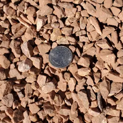Blush 1 inch gravel, featuring a delicate blend of stones in soothing blush tones, with a quarter placed for size comparison. Exclusively available at Albuquerque Landscape Supply, this premium gravel adds a touch of elegance to any landscape. Use it for pathways, garden borders, or as a decorative element to create a tranquil and inviting outdoor retreat.