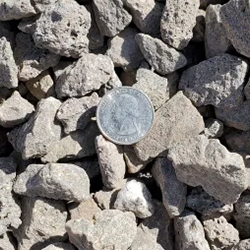 Medium-sized gravel in earthy tones of brown and gray, showcased with a quarter for scale. Available at Albuquerque Landscape Supply, this decorative gravel adds natural beauty and texture to your landscaping projects. Create stunning pathways, define garden areas, or add visual interest to outdoor spaces near you with this versatile and high-quality gravel.