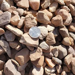 Mountainair Brown 1 inch gravel, showcasing a natural and earthy blend of stones in varying shades of brown, accompanied by a quarter for size reference. Available at Albuquerque Landscape Supply, this high-quality gravel adds texture and warmth to outdoor spaces. Use it for pathways, garden borders, or as a decorative element to enhance the natural beauty of your landscape design.