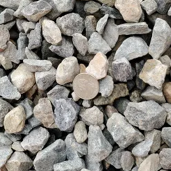 Gray crushed 7/8 inch gravel, featuring a mix of textured stones in varying shades of gray, showcased with a quarter for scale. Available at Albuquerque Landscape Supply, this high-quality gravel adds depth and visual interest to your outdoor space. Use this versatile material for pathways, driveways, or as a striking decorative element, bringing sophistication to your landscape design.